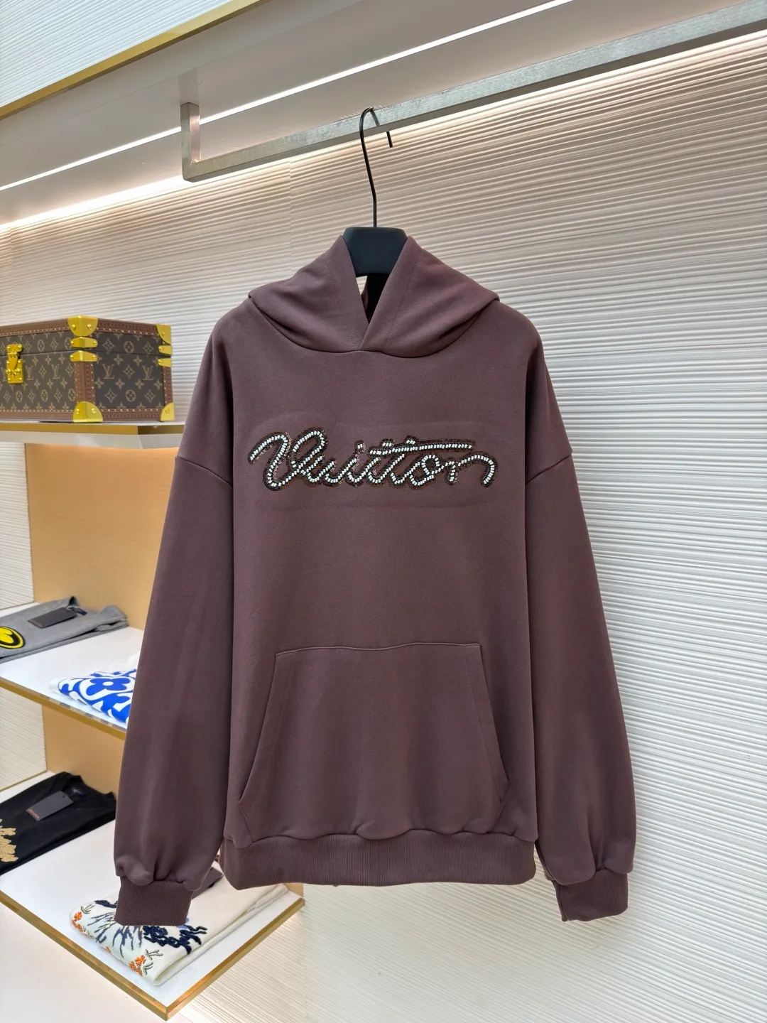 LOUIS VUITTON beaded embroidered letter hooded sweatshirt ●Item number: 1682118-A60 ●Material: pure cotton fish scale base fabric ●Technology: Pearl embroidery production ●Color: brown ●Version: fitted version ●Weight: about 830 grams ●Size: S-M-L-XL ●Description: The fabric is made of 26S double yarn + 10S fish scale bottom brushed fabric, weight 380g, with 21S double yarn 2*2 rib, weight 380g. This kind of fabric is treated with fleece to form a layer of soft and plump fluff on the inside; the improved fish scale knitting method forms a delicate concave and convex texture on the bottom surface, similar to the arrangement of fish scales. Effectively increases the air storage layer and improves thermal insulation performance. The front of the fabric is smooth and smooth, while the back is soft and waxy. It has excellent moisture absorption, breathability, wrinkle resistance and drape, and is thicker and crisper than ordinary sweatshirt materials. It gives clothes excellent warmth retention, breathability and skin-friendly touch. The Vuitton script on the chest is embroidered with beads. During the embroidery process, tiny beads are fixed on the fabric together with embroidery thread. The direct characteristics brought by this process are a strong three-dimensional sense, a unique sense of weight and a reflective effect that changes with the light. The overall wiring is straight and delicate, the fabric is comfortable and soft, and the color is consistent without color difference. It can be matched with the same style to create a fashionable look and control various occasions. Customized accessories, complete with three standards, same style for men and women!